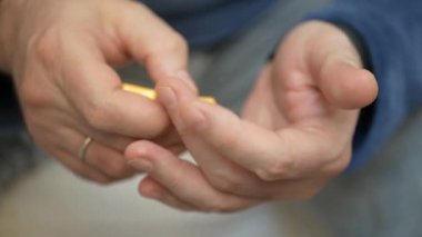 Erkek eli su toplayan torbalardan hap alır. Erkek eli kapalı beyaz turuncu yuvarlak tablet dökün. Elinde tıbbi doz hapı var. Grip, yetişkin, soğuk algınlığı, hastalık, virüs, ağır çekim hapları..