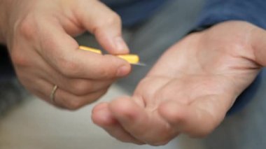 Erkek eli su toplayan torbalardan hap alır. Erkek eli kapalı beyaz turuncu yuvarlak tablet dökün. Elinde tıbbi doz hapı var. Grip, yetişkin, soğuk algınlığı, hastalık, virüs, ağır çekim hapları..
