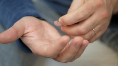 Erkek eli su toplayan torbalardan hap alır. Erkek eli kapalı beyaz turuncu yuvarlak tablet dökün. Elinde tıbbi doz hapı var. Grip, yetişkin, soğuk algınlığı, hastalık, virüs, ağır çekim hapları..