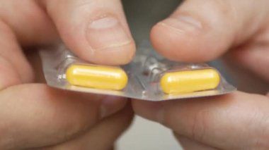 Erkek eli su toplayan torbalardan hap alır. Erkek eli kapalı beyaz turuncu yuvarlak tablet dökün. Elinde tıbbi doz hapı var. Grip, yetişkin, soğuk algınlığı, hastalık, virüs, ağır çekim hapları..