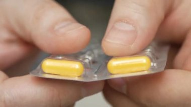 Erkek eli su toplayan torbalardan hap alır. Erkek eli kapalı beyaz turuncu yuvarlak tablet dökün. Elinde tıbbi doz hapı var. Grip, yetişkin, soğuk algınlığı, hastalık, virüs, ağır çekim hapları..