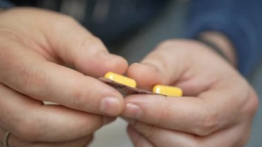 Erkek eli su toplayan torbalardan hap alır. Erkek eli kapalı beyaz turuncu yuvarlak tablet dökün. Elinde tıbbi doz hapı var. Grip, yetişkin, soğuk algınlığı, hastalık, virüs, ağır çekim hapları..