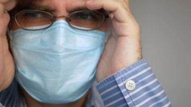 Yüzünde antivirüs koruması maskesi olan üzgün bir adam derin bir nefes alıyor, virüsü seyrediyor, covid-19 haberleri korkmuş bir bakış ve hızlı nefes alıyor.