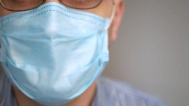 Yüzünde antivirüs koruması maskesi olan üzgün bir adam derin bir nefes alıyor, virüsü seyrediyor, covid-19 haberleri korkmuş bir bakış ve hızlı nefes alıyor.