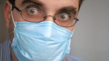Yüzünde antivirüs koruması maskesi olan üzgün bir adam derin bir nefes alıyor, virüsü seyrediyor, covid-19 haberleri korkmuş bir bakış ve hızlı nefes alıyor.