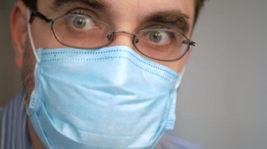 Yüzünde antivirüs koruması maskesi olan üzgün bir adam derin bir nefes alıyor, virüsü seyrediyor, covid-19 haberleri korkmuş bir bakış ve hızlı nefes alıyor.