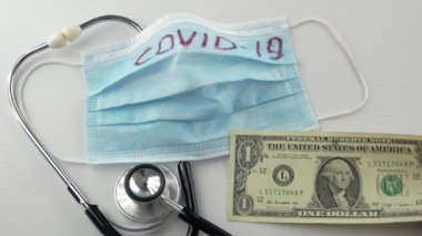 Virüs koruyucu, koronavirüs önleme maskesi, COVID-19, stetoskop, beyaz arka planda para. Ödeme son para. Virüsün tedavisi için. Kriz parası bitti. Yakın plan.