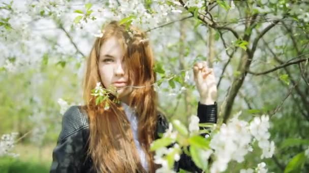Rödhårig tjej i blommande blommor — Stockvideo