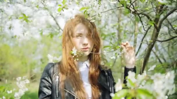 Roodharige meisje in de bloeiende bloemen — Stockvideo