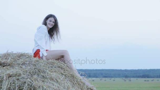 Красивая молодая женщина сидит на сене — стоковое видео