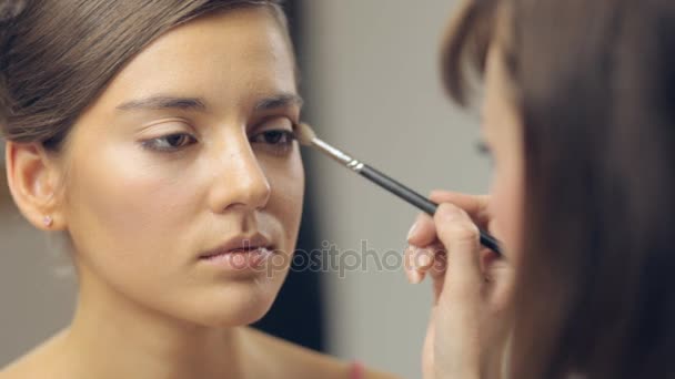 Makeup artist applying makeup on cheekbones. Panning — Stock Video