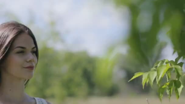 Mooie jongedame met takken vol met groene bladeren — Stockvideo