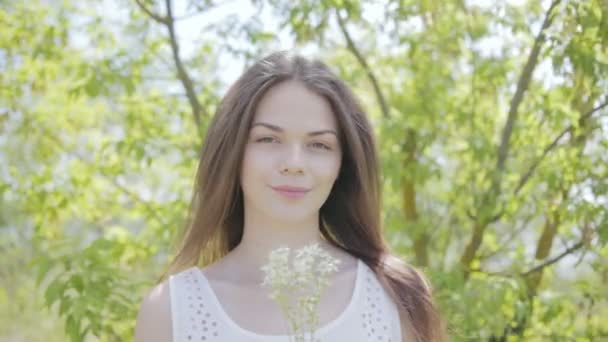 Joven mujer bonita con flor de prado blanco. Movimiento lento — Vídeos de Stock