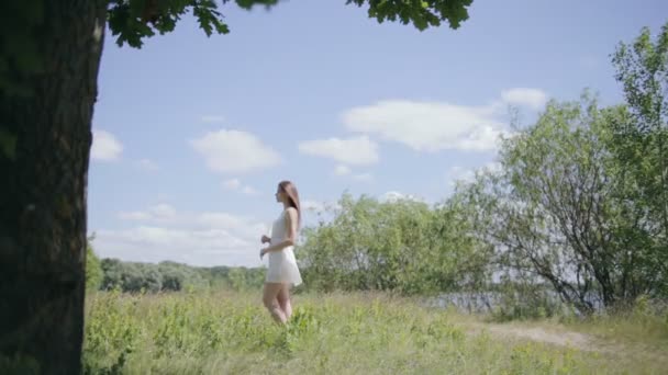 Joven mujer bonita en el prado. Disfrutando de la luz del sol. Movimiento lento — Vídeos de Stock