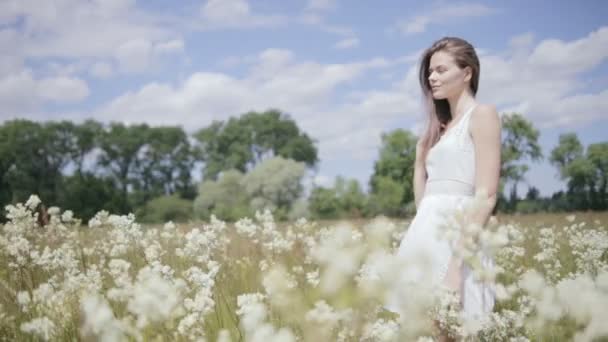 Молодая красивая женщина посреди цветочного луга, смотрит в сторону — стоковое видео