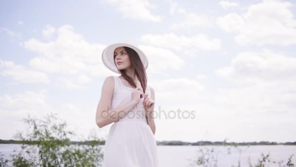 Jeune jolie femme près de l'eau avec ciel plein de nuages — Video