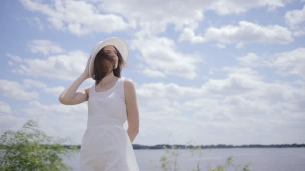 Joven mujer bonita cerca del agua con el cielo lleno de nubes — Vídeos de Stock