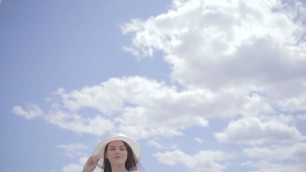 Молода красива жінка біля води з небом, повним хмар — стокове відео