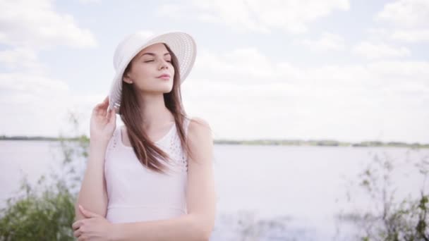 Young pretty woman near water with sky full of clouds — Stock Video