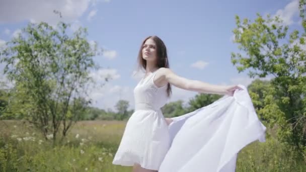 Joven mujer bonita sosteniendo tela blanca en el viento. Tiro medio — Vídeos de Stock