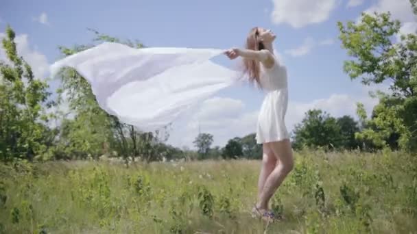 Joven mujer bonita sosteniendo tela blanca en el viento. Disparo completo — Vídeos de Stock