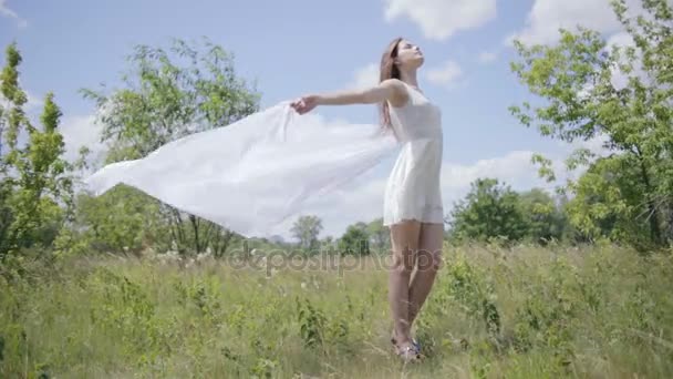 Joven mujer bonita sosteniendo tela blanca en el viento. Disparo completo — Vídeos de Stock