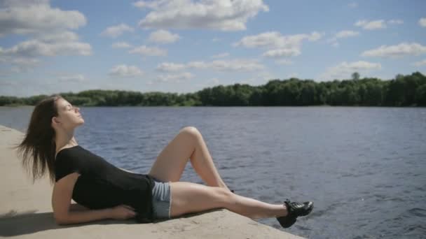 Nehir kenarında Kapalı gözlerle oturan genç güzel kadın — Stok video
