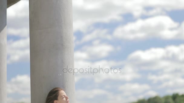 Молода красива жінка сидить біля річки з закритими очима — стокове відео