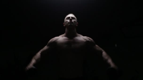 Bodybuilder training in donker — Stockvideo