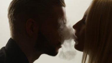 Kadın duman öpücük adama veriyor.