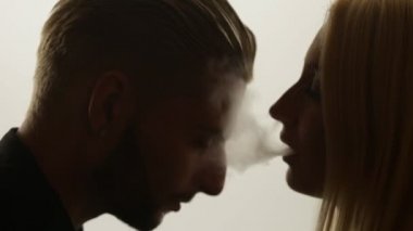 Kadın duman öpücük adama veriyor.