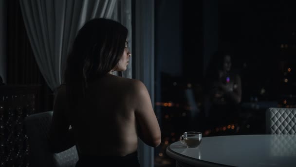 Mujer sentada y mirando a la ventana — Vídeo de stock