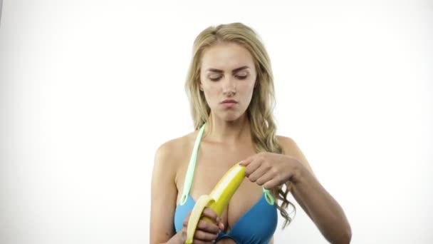 Νεαρή Γυναίκα Στο Μπικίνι Απολέπιση Και Τρώει Μπανάνα — Αρχείο Βίντεο