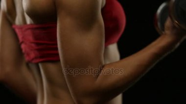 Genç sarışın bir kadın siyah egzersiz yaparak dumbbells ile kırmızı mayo yerleştirmek. sorunsuz döngü