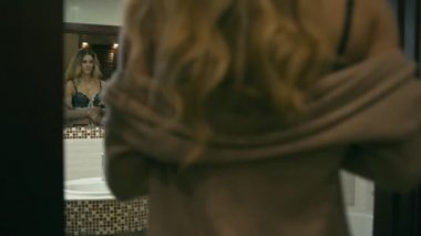 Yorgun üzgün sarışın kadın iç çamaşırı banyoda ayna yakınındaki bir şarap içiyor