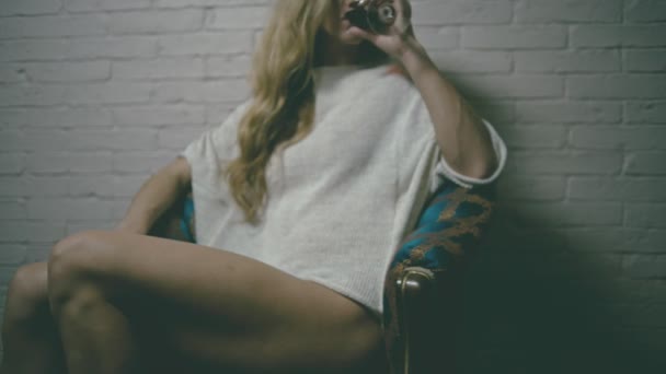 巻き毛長髪の金髪の女性ワイングラス肘掛け椅子に座っていると笑顔と — ストック動画