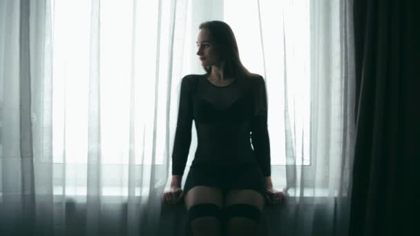 中年窓際のセクシーな衣装で挑発的な女性 シームレスなループ — ストック動画