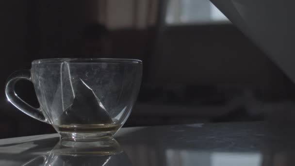 Warm water in beker gieten met theezakje — Stockvideo
