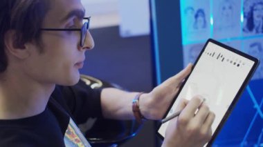 Genç adam tablet ve elektronik kalem kullanarak resim çiziyor, yavaş çekim, sığ alan derinliği