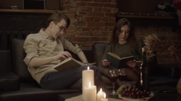 黒いソファの上のカップル読書本 フィールドの浅い深さ スローモーション — ストック動画