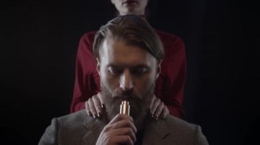 Sakallı adam sigara içiyor, kadın sakalına dokunuyor yumuşak, ağır çekimde.