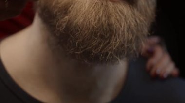 Kadın erkeğin sakalını tarıyor, sığ bir alan derinliği, ağır çekim.