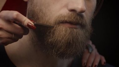 Kadın erkeğin sakalını tarıyor, sığ bir alan derinliği, ağır çekim.