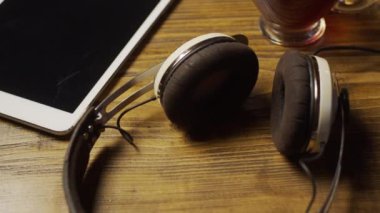 Tablet, kulaklık ve çay ahşap masada, ağır çekim.