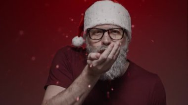 Noel Baba 'nın kırmızı arka planda yaptığı portre - kameraya kırmızı parıltı üfleme, yavaş çekim