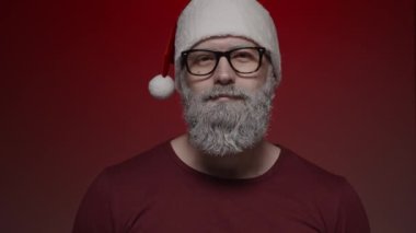 Noel Baba 'nın kırmızı arka planda yaptığı portre, onay veren, ağır çekimde işaret dilini gösteriyor.