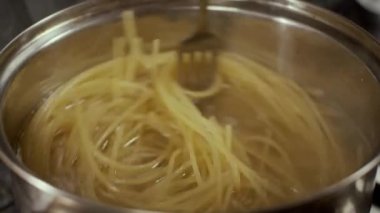 Spagettiyi tavada çatalla karıştırmak, ağır çekim, sığ alan derinliği