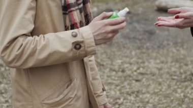Corona virüsü bulaşmasını önlemek için dezenfektan kullanan genç kadın ve erkek, sadece elleri görünüyor. Yavaş çekim