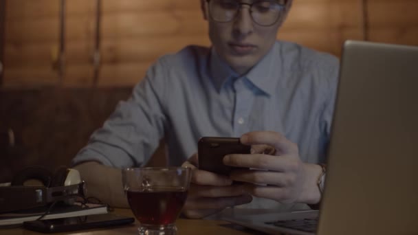 Young man working with laptop and smartphone — Stock Video