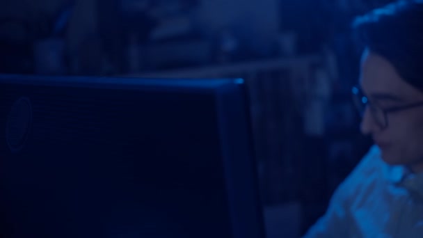 Jeune homme à lunettes travaillant à l'ordinateur, réflexion du moniteur à lunettes, ralenti, faible profondeur de champ 